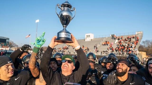 Northeastern State hoists a DII football bowl trophy.